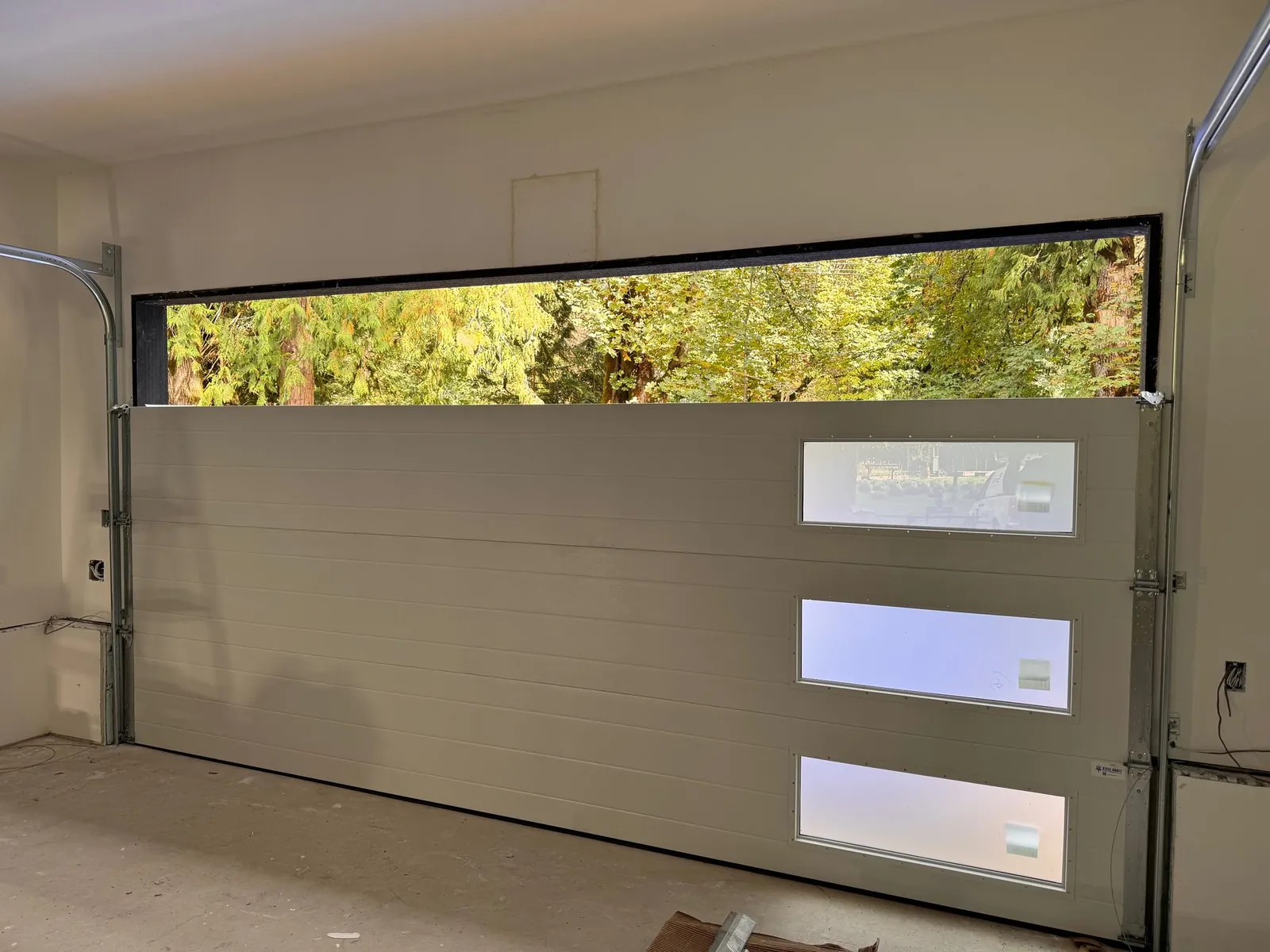 Newly installed modern flush garage door with a full-width top window on a Tsawwassen home