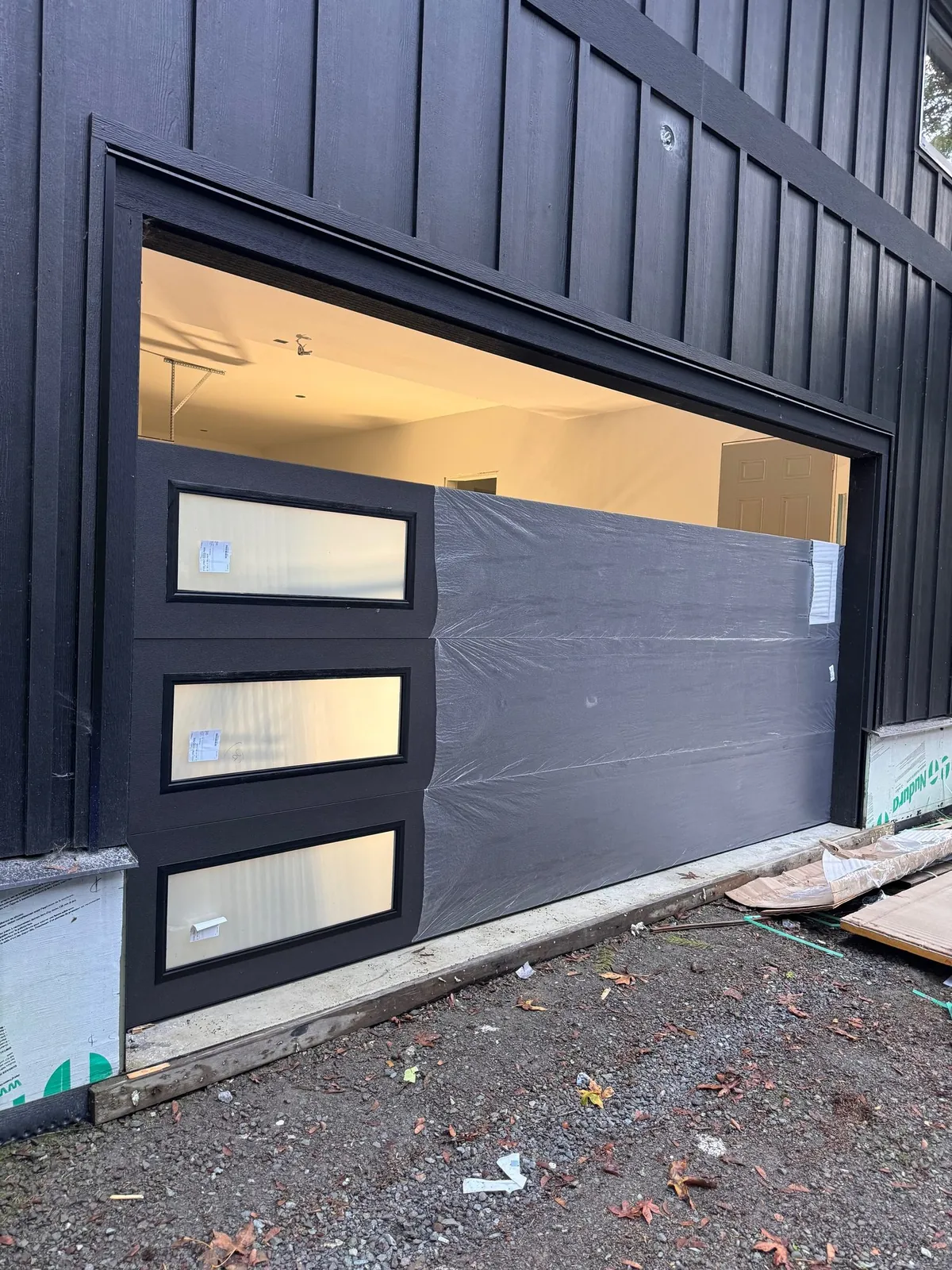Modern black-framed garage door with frosted window panels on a contemporary Delta BC home