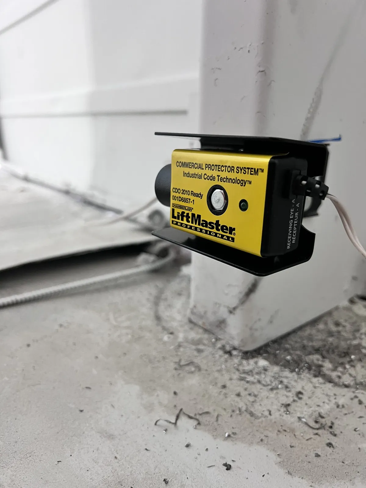 LiftMaster safety photo-eye sensor mounted near the garage floor