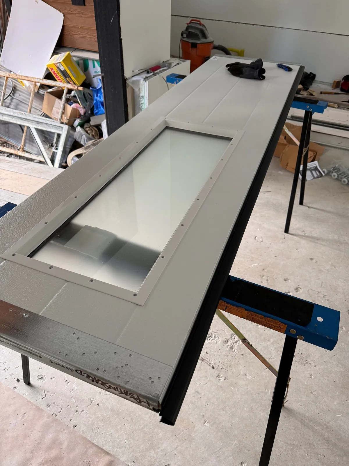 New garage door panel with a glass window prepared on sawhorses during installation in Delta BC