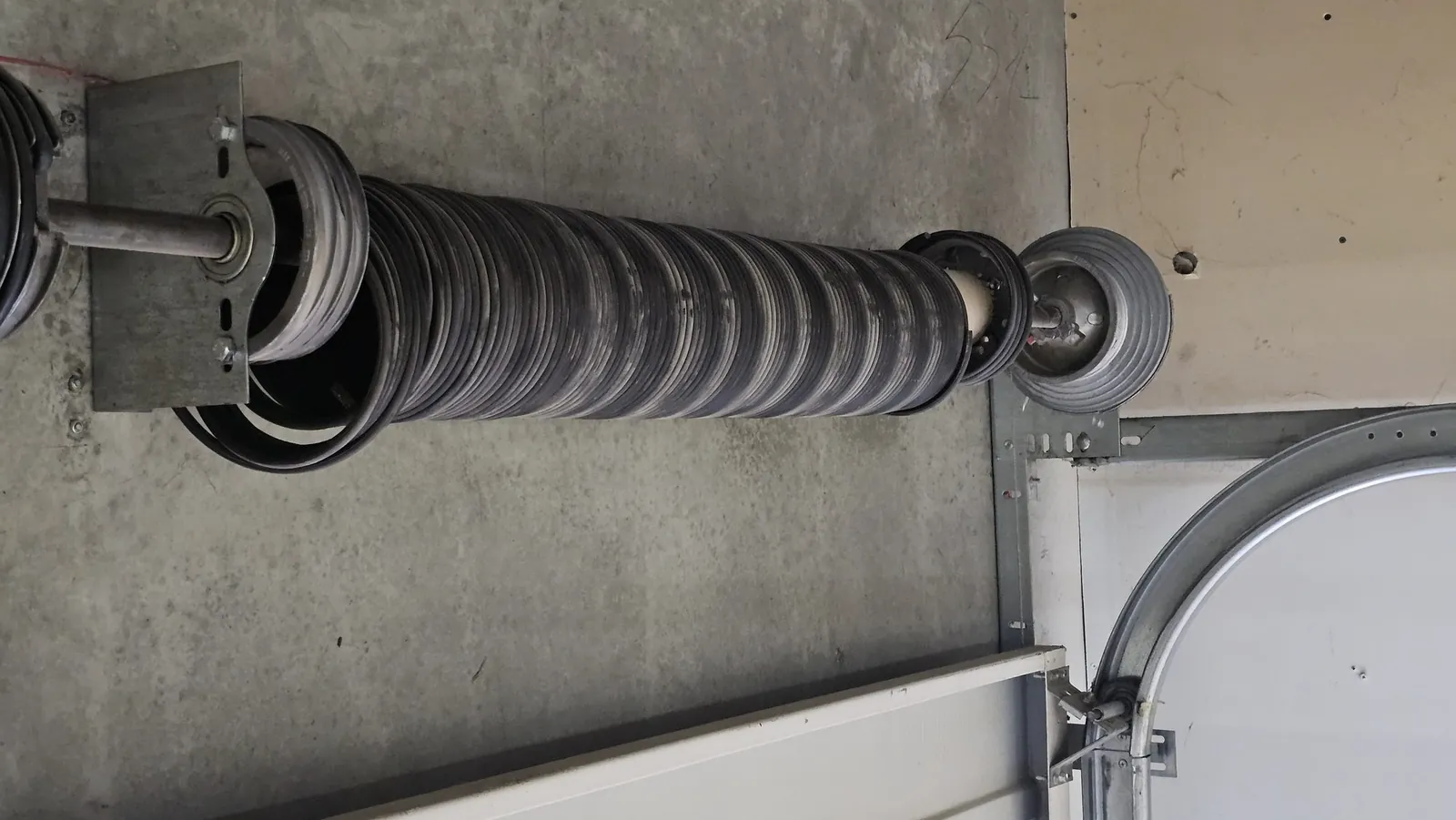 Garage door torsion spring assembly on the shaft above a door — broken spring repair in Tsawwassen