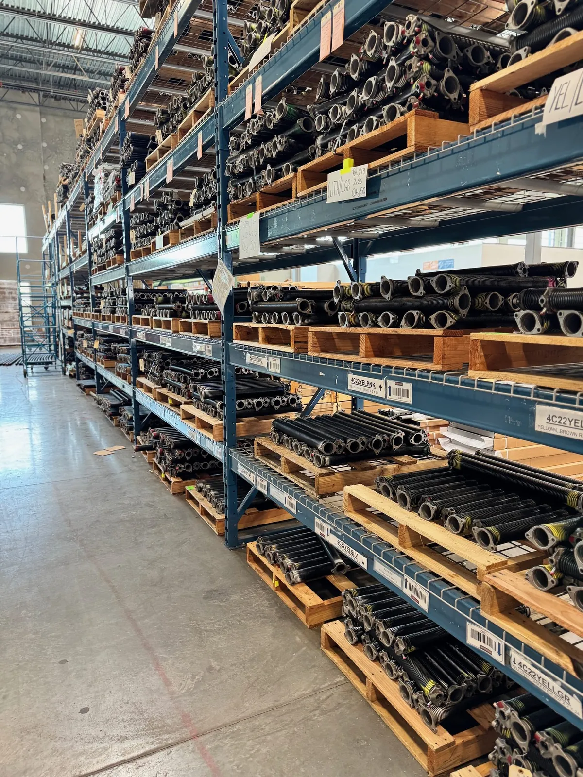 Warehouse racks stocked with garage door torsion springs in every size