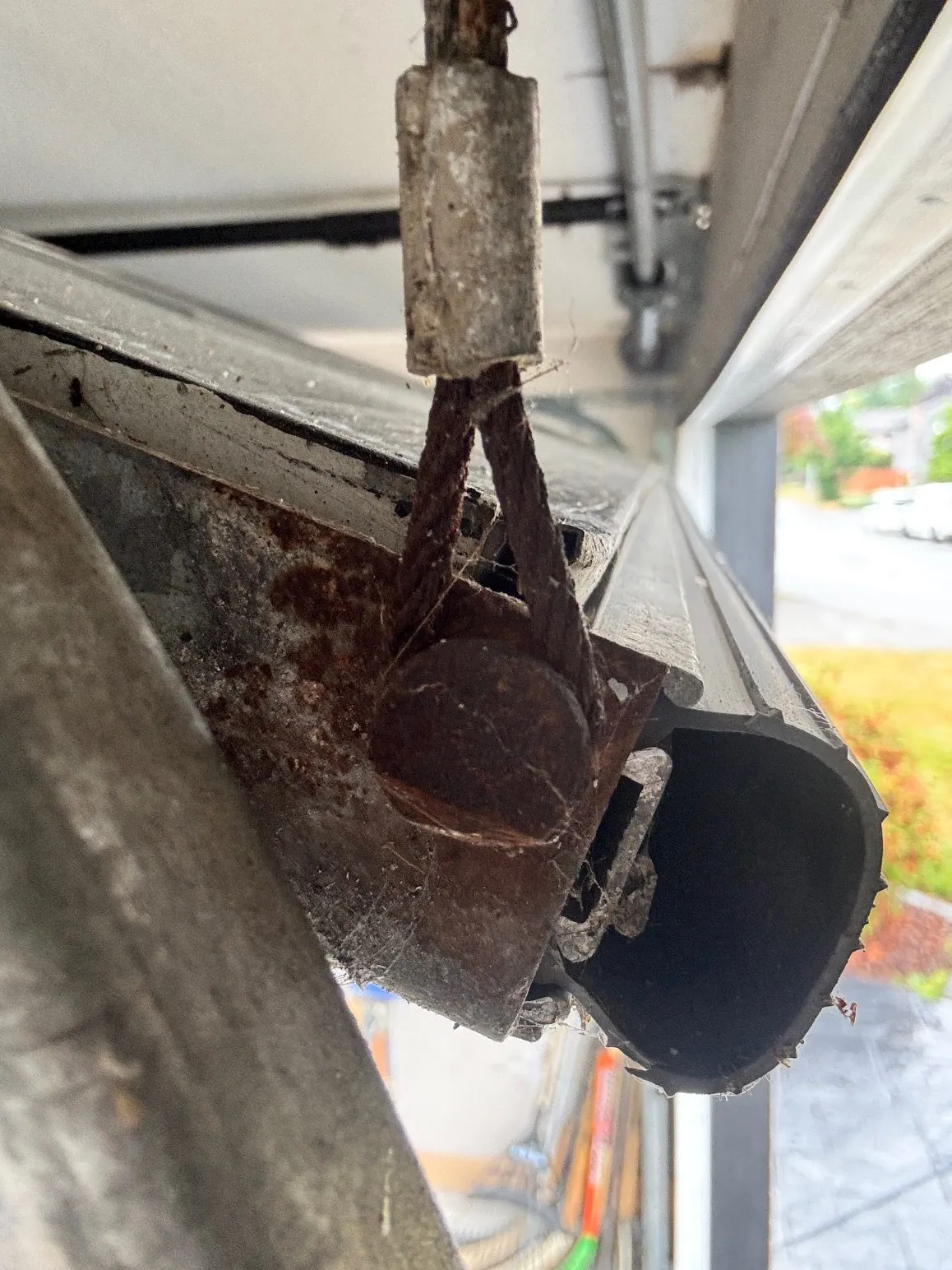 Rusted, worn garage door cable and hardware on an exposed Boundary Bay home