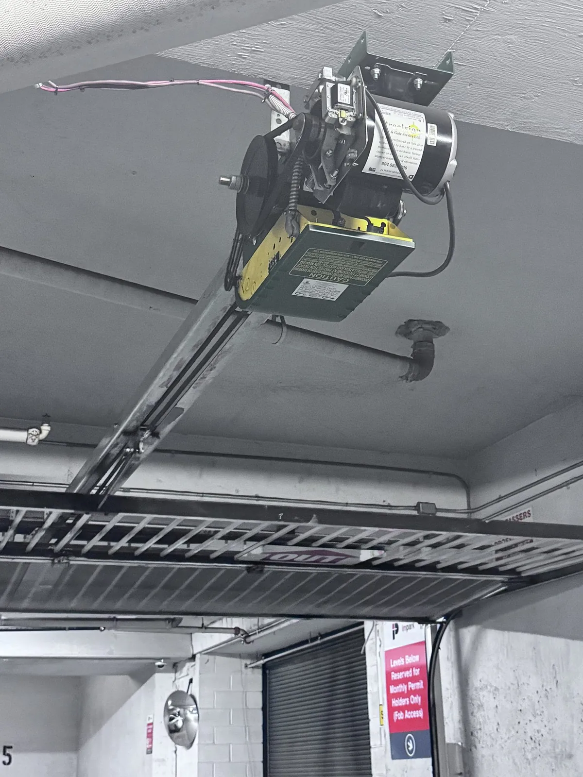 Heavy-duty commercial jackshaft operator mounted beside a parkade roll-up door at a Tsawwassen building